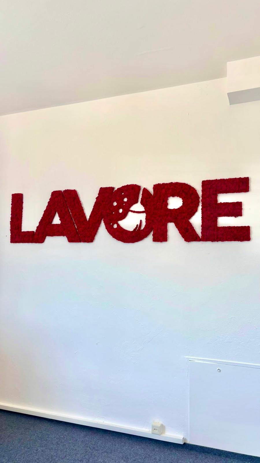 Červené machové písmená LAVORE osadené na stene